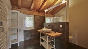 A modern bathroom with a wooden ceiling, a white sink, and a mirror.