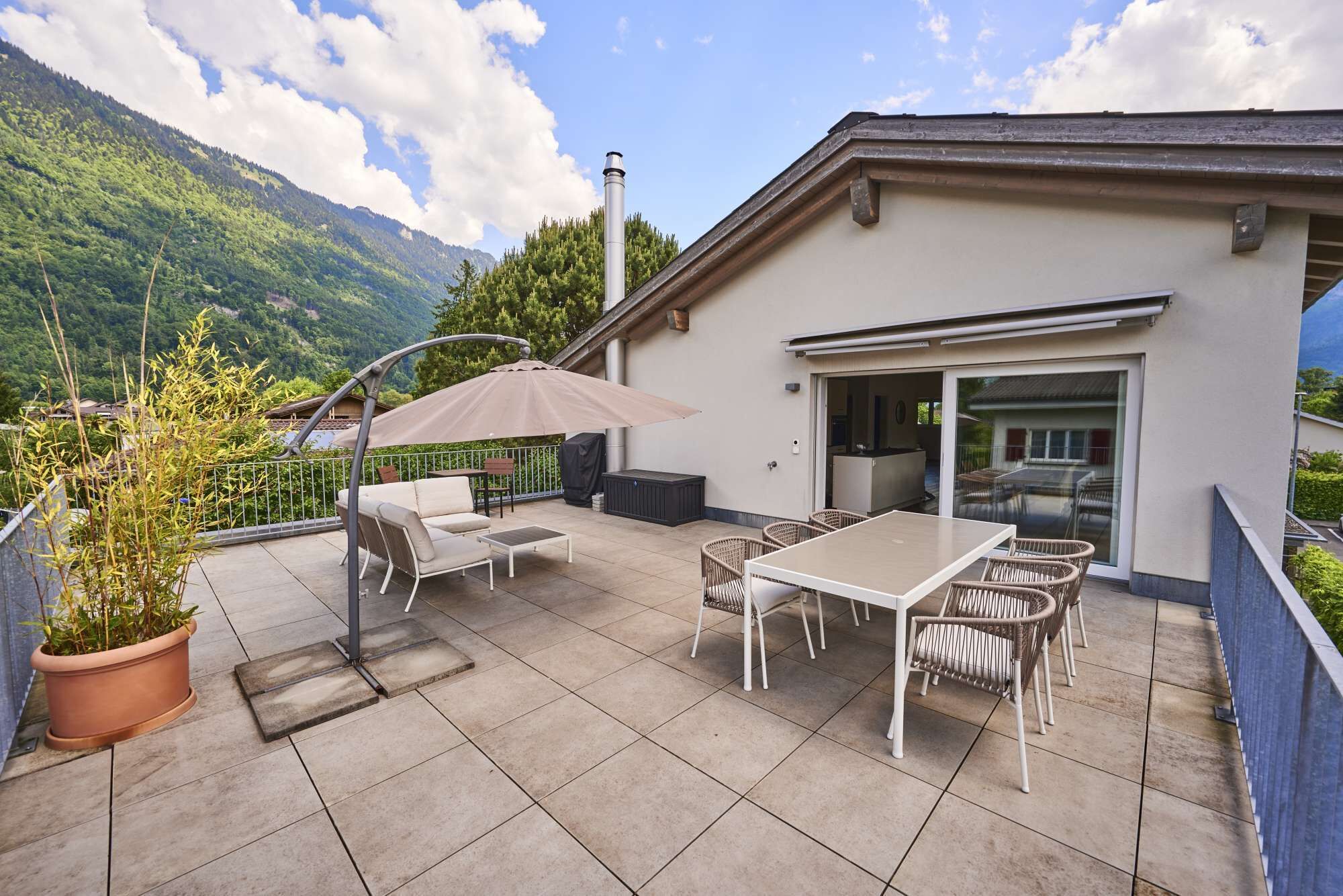Une terrasse avec des meubles d’extérieur, une table et une plante en pot.