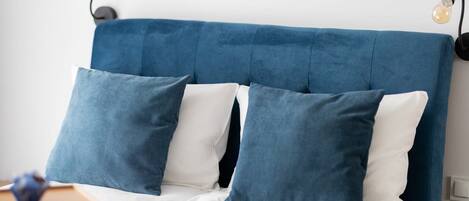 A bed with a blue headboard, white bedding, and two blue pillows.