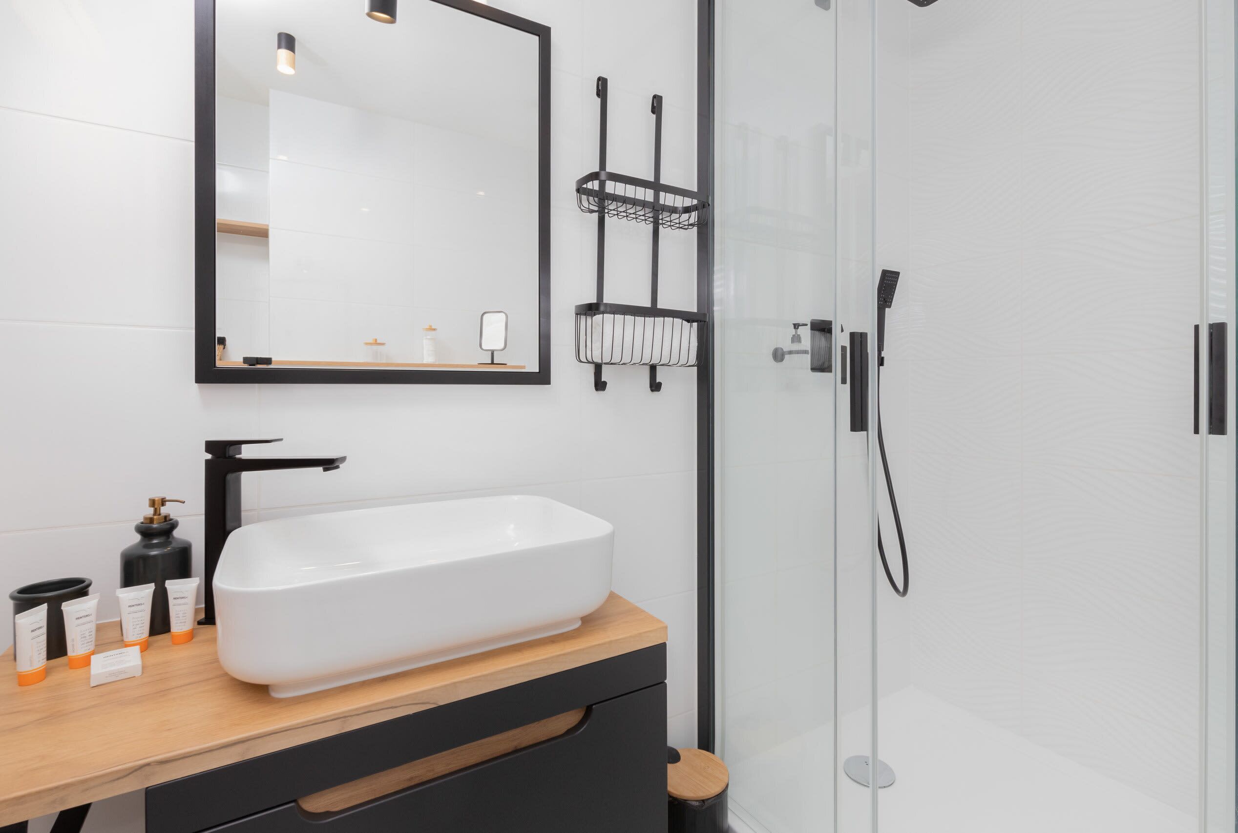 A modern bathroom with a walk-in shower, sleek black fixtures, and a spacious vanity area.

