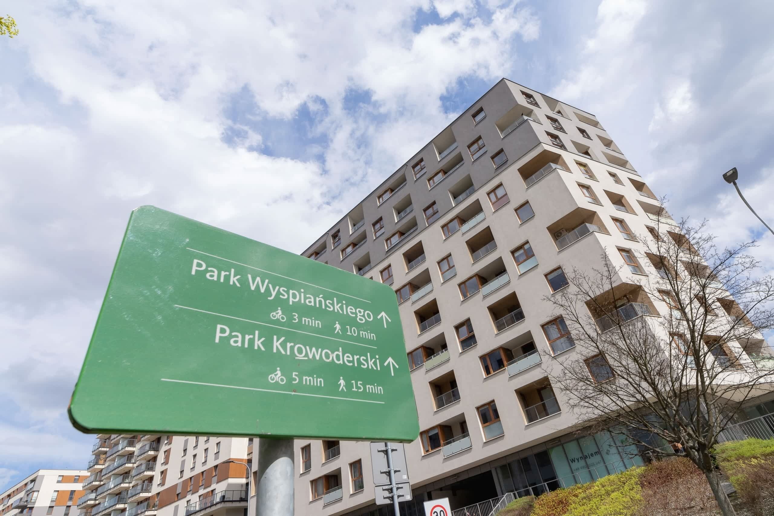 Ein Hinweisschild mit Pfeilen, die zu Park Wyspianska und Park Krowoderski zeigen. Die Gehzeiten werden mit 3 bis 10 Minuten und 5 bis 15 Minuten angegeben.