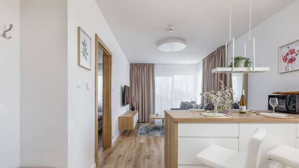 Una cocina moderna con encimera de madera, armarios blancos y una lámpara colgante.