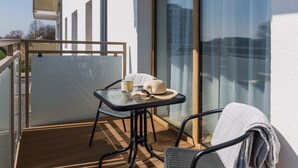 Un balcón con puerta de cristal, una mesita con una silla, y una toalla colgada sobre la silla.