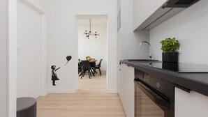 A modern kitchen with white cabinets, a black countertop, and a built-in oven. - Stylish Apartment in the Center | Air Conditioning (Warszawa)