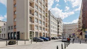 A multi-story building with balconies, a parking area with cars, and a clear sky. - Stylish Apartment in the Center | Air Conditioning (Warszawa)