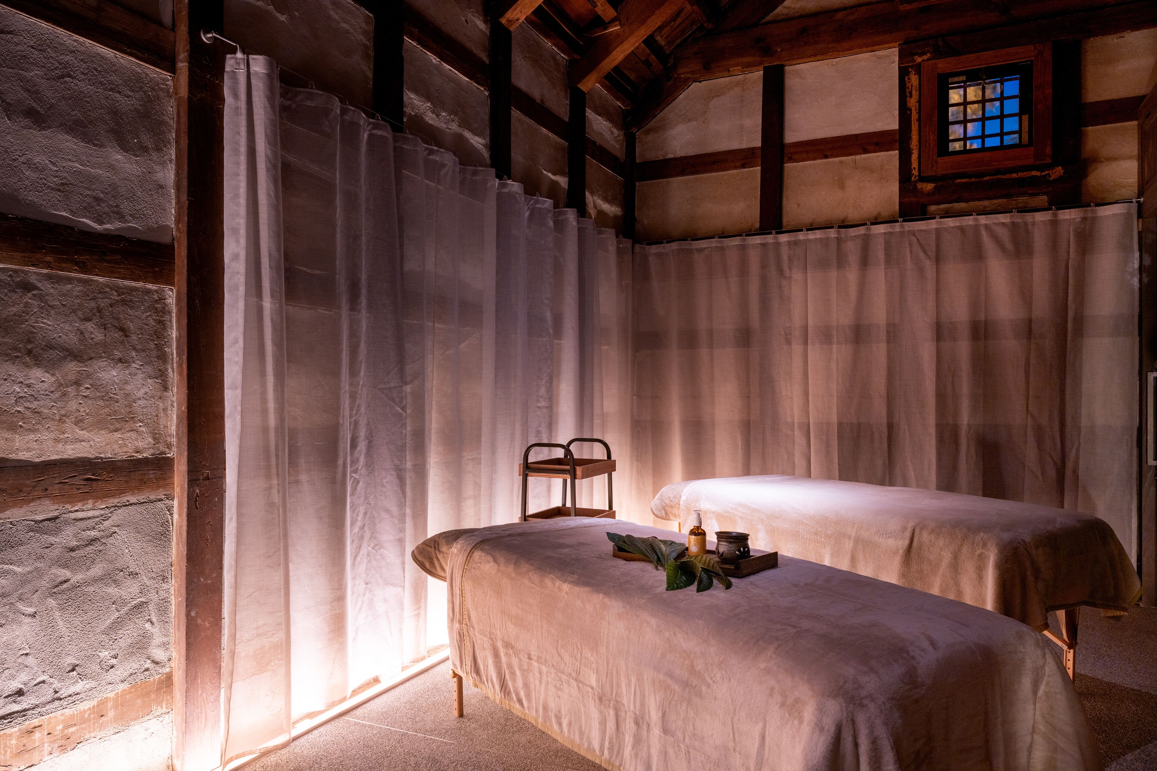 A room with two beds, a wooden ceiling, and a window with a view.