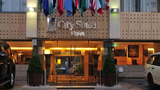 The exterior of the City Suite Hotel with a modern facade, a prominent entrance, and multiple flags displayed above. - City Suite Hotel (Beirut)