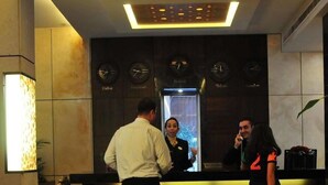 A hotel reception area with a modern design, featuring a reception desk, a digital clock displaying time, and a wall-mounted elevator. - City Suite Hotel (Beirut)