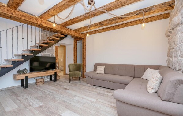 Un salon moderne avec un escalier en bois, un canapé et un téléviseur.