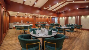 Une salle de conférence dotée de tables rondes et de chaises vertes, ainsi que de verres et de serviettes en papier.