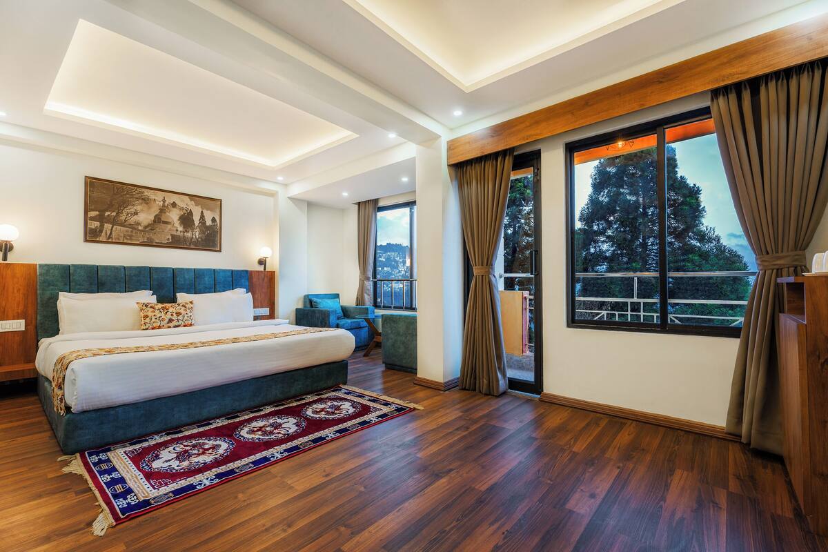 A bedroom with a large bed, a view of the outdoors, and a wooden ceiling.