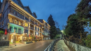 Un hôtel à plusieurs étages doté de balcons, une rue pavée et une rambarde le long du trottoir.