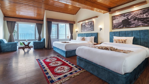Une chambre d’hôtel avec deux lits, une grande fenêtre, un plafond en bois et une vue sur la mer.