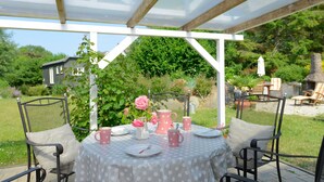 An outdoor patio with a table set for dining, surrounded by chairs, and a pergola overhead. - Pretty bungalow with fireplace in Boltenhagen (Ostseebad Boltenhagen)