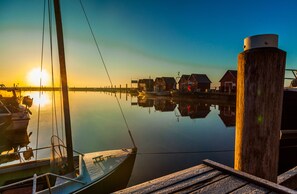 Een rustige jachthaven met aangemeerde boten en houten gebouwen die de zonsondergang weerspiegelen.