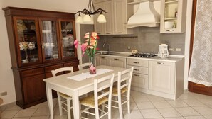 Una cocina con mesa, sillas, un armario y una estufa.