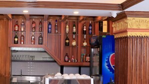 A bar area with a pepsi refrigerator, a coffee machine, and various liquor bottles. - Satkar Hotel and Spa (Kathmandu)