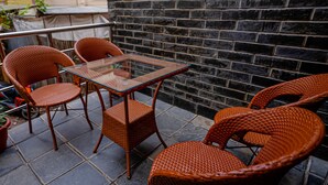 A patio area with wicker chairs and a glass table, set against a brick wall. - Satkar Hotel and Spa (Kathmandu)