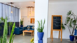 A modern interior with a seating area, a chalkboard menu, and potted plants. - HOTEL ACRUS (Galle)