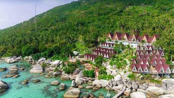 A resort with multiple bungalow-style buildings, a rocky shoreline, and lush greenery.
