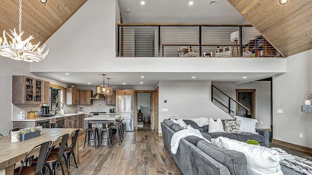 Un loft espacioso con comedor, cocina y un sofá grande de color gris.