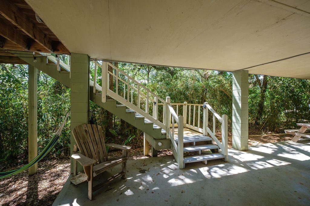 Un escalier en bois mène à un espace extérieur abrité, où se trouvent un banc et une table de pique-nique.