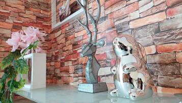 A room with a brick wall, a glass table, and decorative items including a tree sculpture and a ceramic frog.
