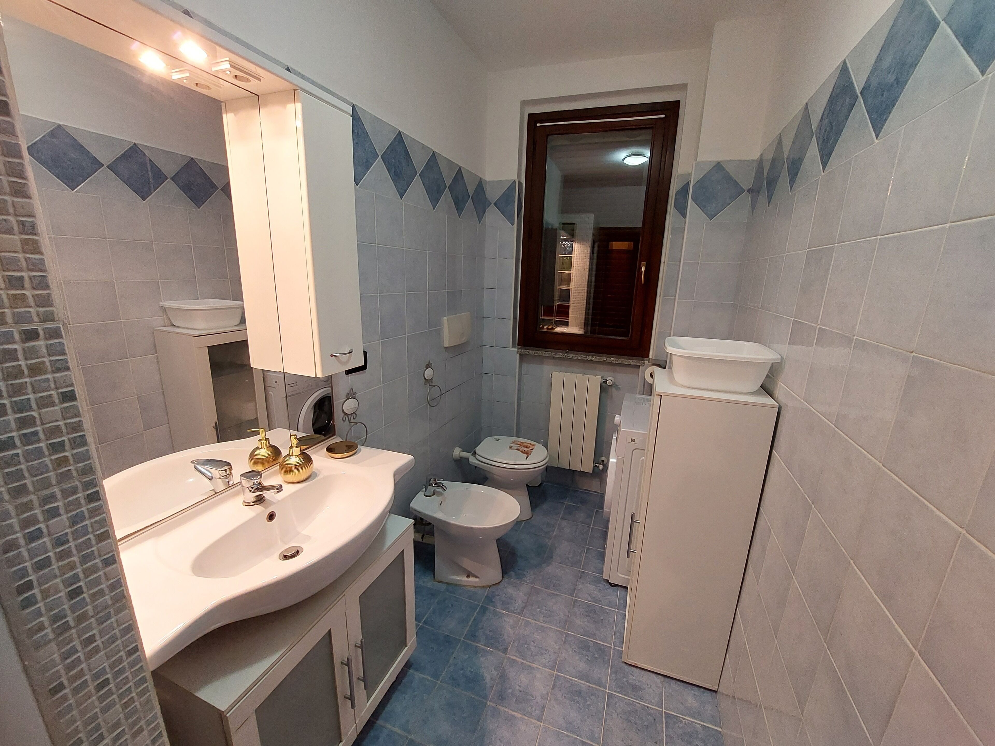 Ein kleines Badezimmer mit Waschbecken, Spiegel, Toilette und einem kleinen Schrank.