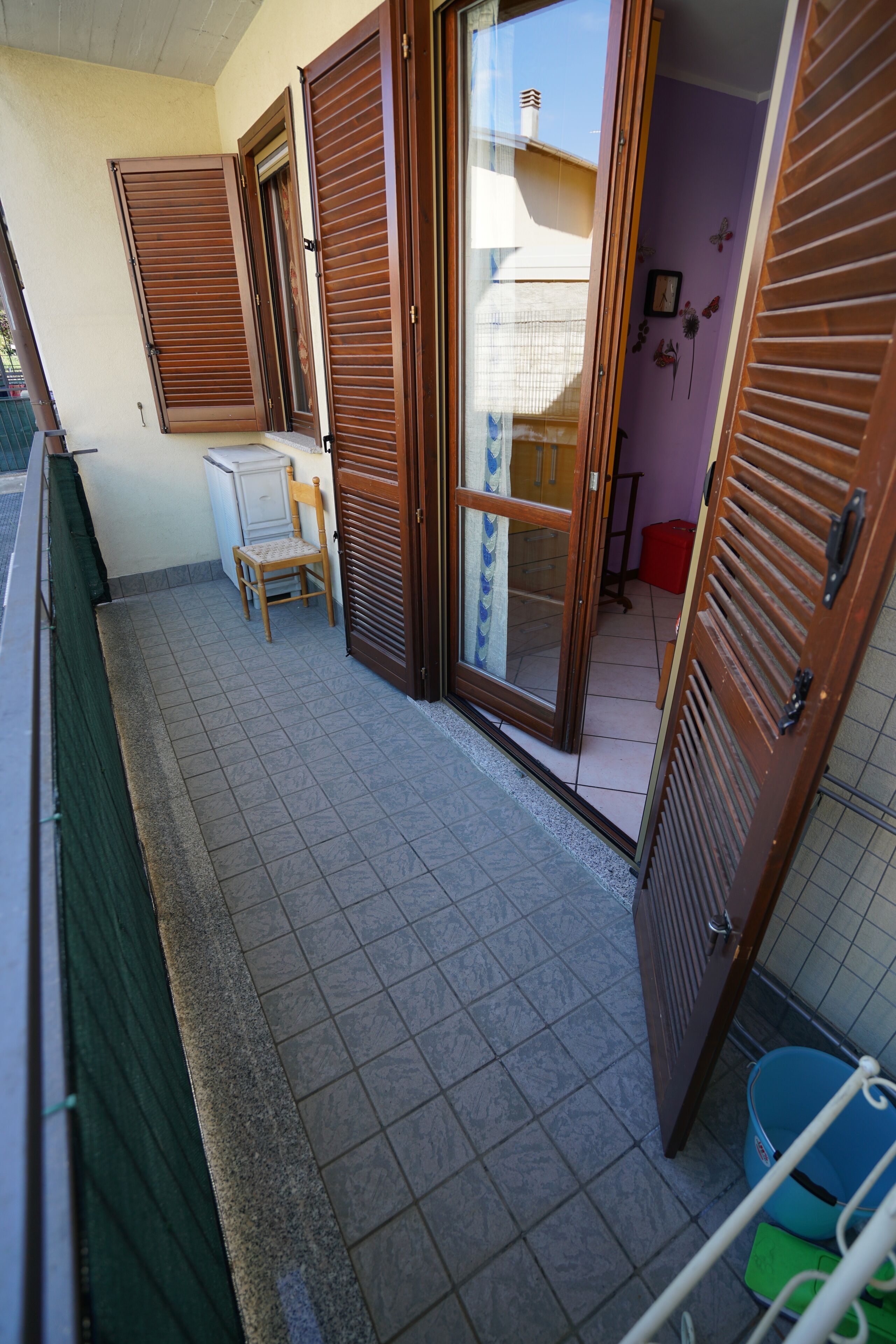 A balcony with a tiled floor, a chair, and a table.