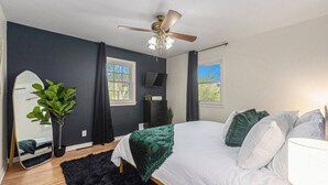 Ein modernes Schlafzimmer mit Bett, Deckenventilator, großem Spiegel und Fenster.