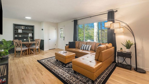 Ein modernes Wohnzimmer mit einer Ledersofa, einem Couchtisch und einem Essbereich mit Holztisch und Stühlen.