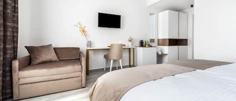 Una habitación de hotel moderna con cama, sofá, escritorio y televisor.