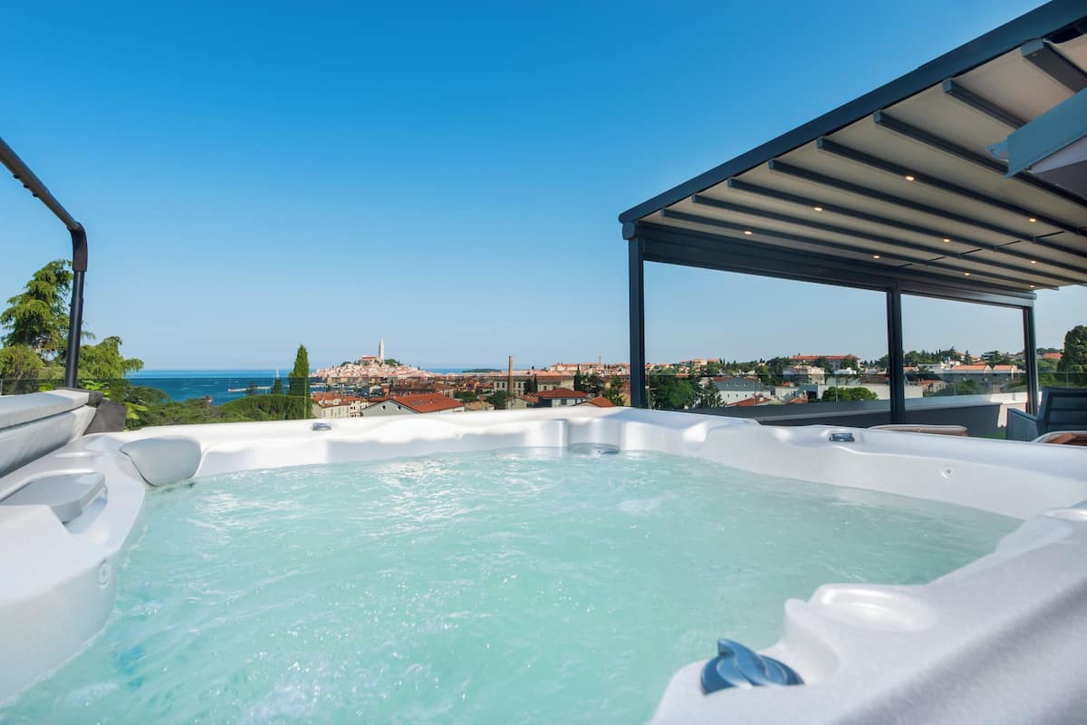 A hot tub with a clear view of the sea and cityscape.