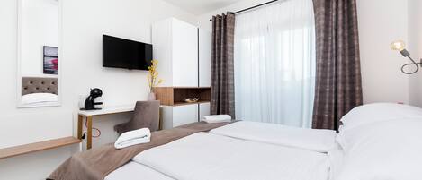 A hotel room with a bed, desk, chair, TV, and curtains.