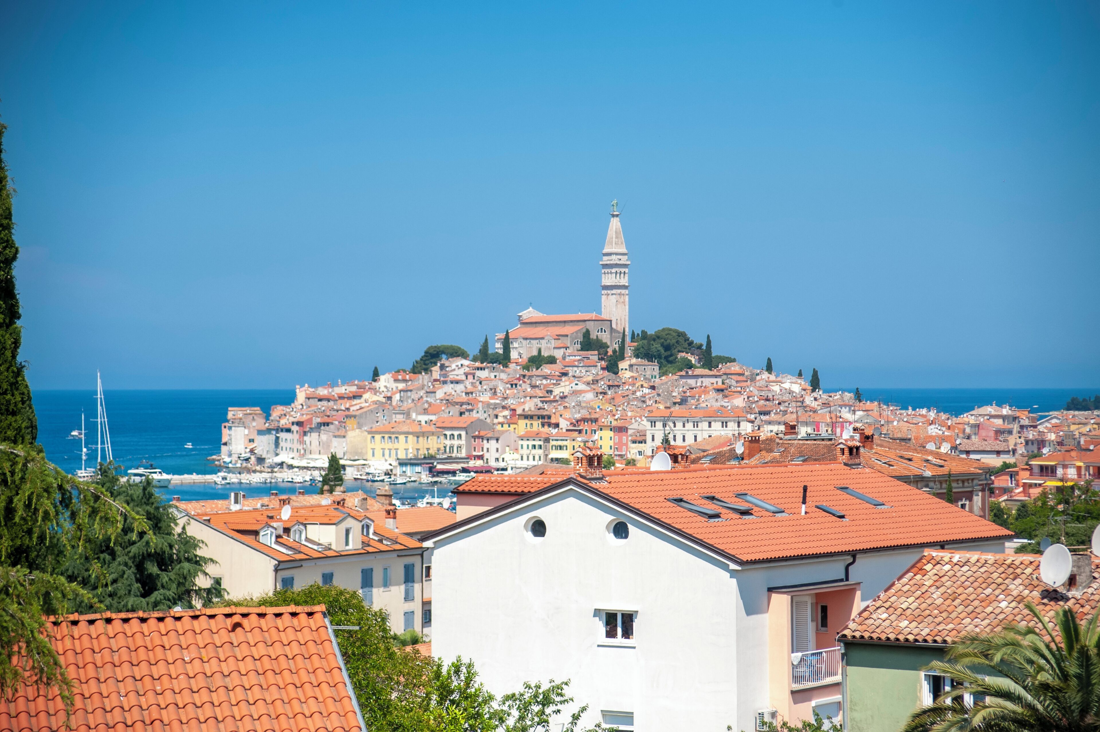 A coastal town with a prominent church on a hill, surrounded by colorful buildings and a marina.