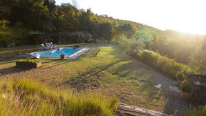 En trädgård med en pool, solstolar och en gräsyta.