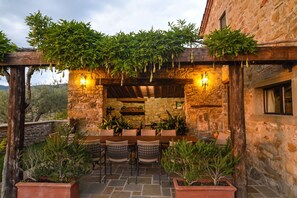 Un patio al aire libre con suelo de piedra, pérgola de madera y plantas en macetas.