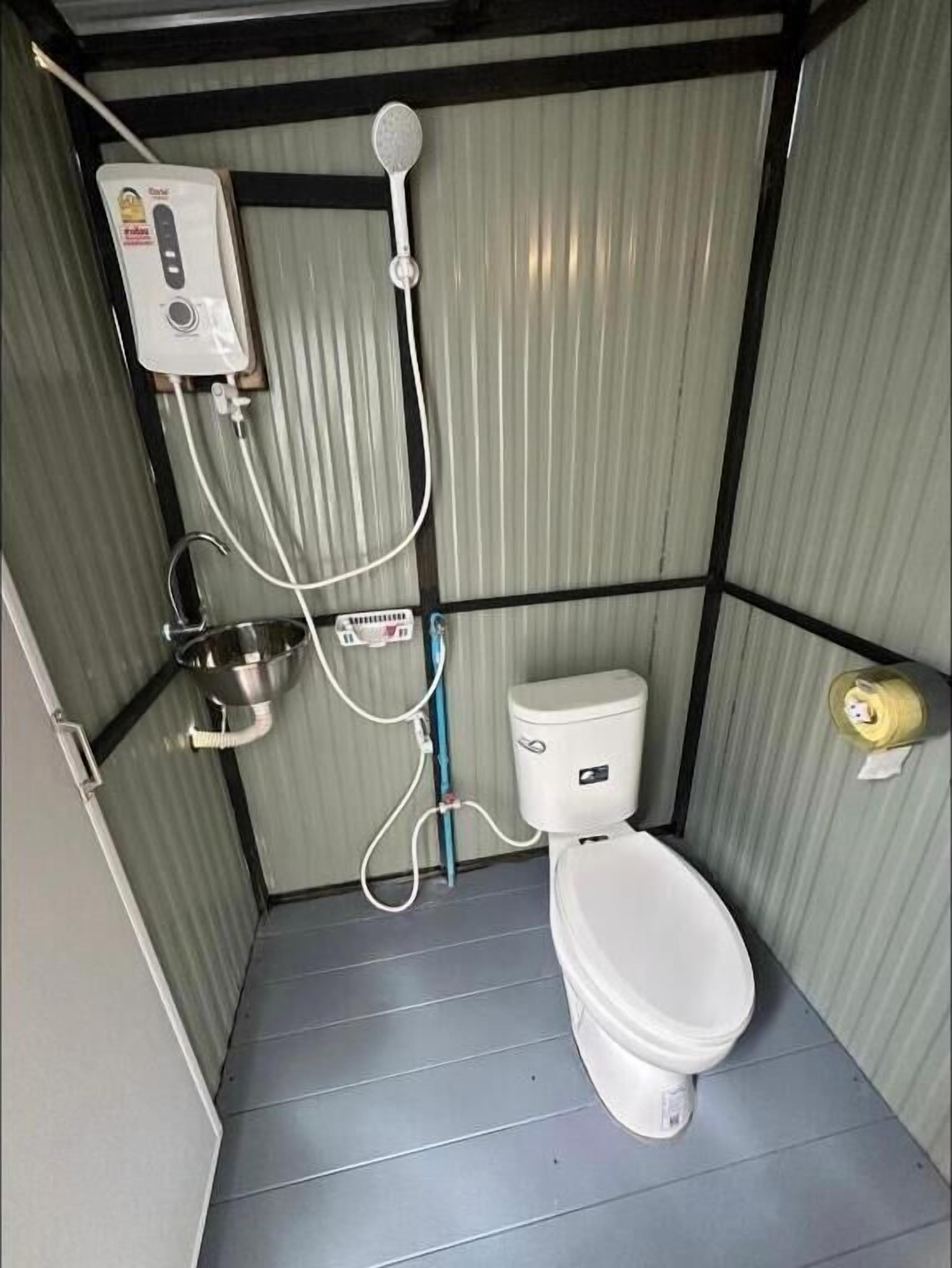 A compact bathroom with a toilet, a shower, and a hand dryer.