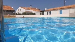 Ein Schwimmbecken mit klarem, blauem Wasser, umgeben von weißen Gebäuden mit roten Ziegeldächern.
