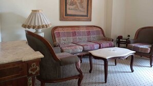 A room with a sofa, armchairs, a table, and a lamp.
