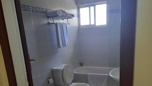 A bathroom with two toilets, a sink, and a bathtub.