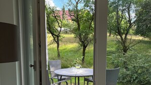 Lasiliukuovi johtaa ulkoterasille, jossa on pyöreä pöytä ja rottinkituolit. Terassin ympärillä on kivilaatoitettu lattia ja nurmialue, jossa kasvaa puita.