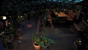 Ein Terrassenbereich im Freien mit Backsteinböden, Holzmöbeln und Blumentöpfen.