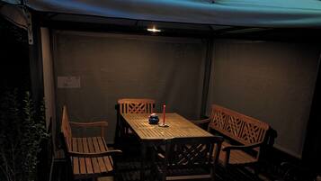 Un patio exterior con una mesa y sillas bajo un toldo blanco.
