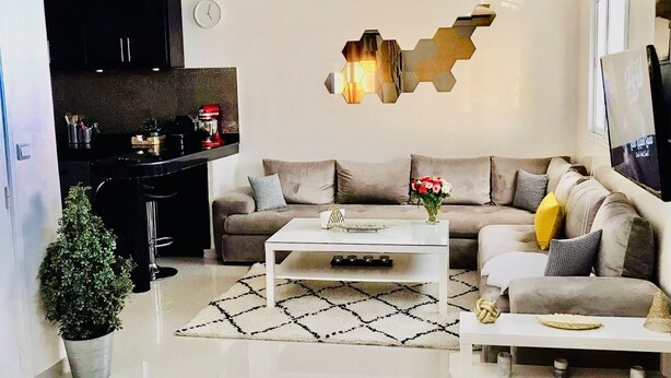 A modern living room with a sofa, coffee table, and a decorative wall piece. - Duplex Calme Cosy 5 Minutes du Centre d Essaouira (Essaouira)