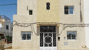 A two-story building with a textured facade, a central entrance with decorative metal gates, and small windows with metal bars. - Duplex Calme Cosy 5 Minutes du Centre d Essaouira (Essaouira)