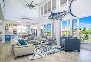 A spacious living area with a large window, a ceiling fan, and a dining area.