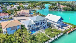 Una extensa propiedad frente al agua con varias construcciones, una piscina y un muelle que se adentra en el agua.