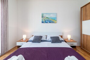 Et hotelværelse med en seng, to sengeborde, et natbord, et billede på væggen og en træskab.