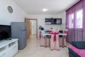 A modern kitchen with a dining area, a TV, and a refrigerator.